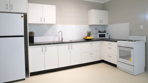 A modern kitchen with white cabinets, a black countertop, a sink, a microwave, and an oven. - Apartments at Mission Beach (Mission Beach)