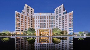 A multi-story hotel with a central courtyard and reflective pool. - Hualuxe Ningbo Harbor City (Ningbo)