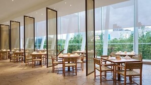 A restaurant with hexagonal tiled flooring, wooden tables and chairs, and large windows offering a view of greenery. - Hualuxe Ningbo Harbor City (Ningbo)