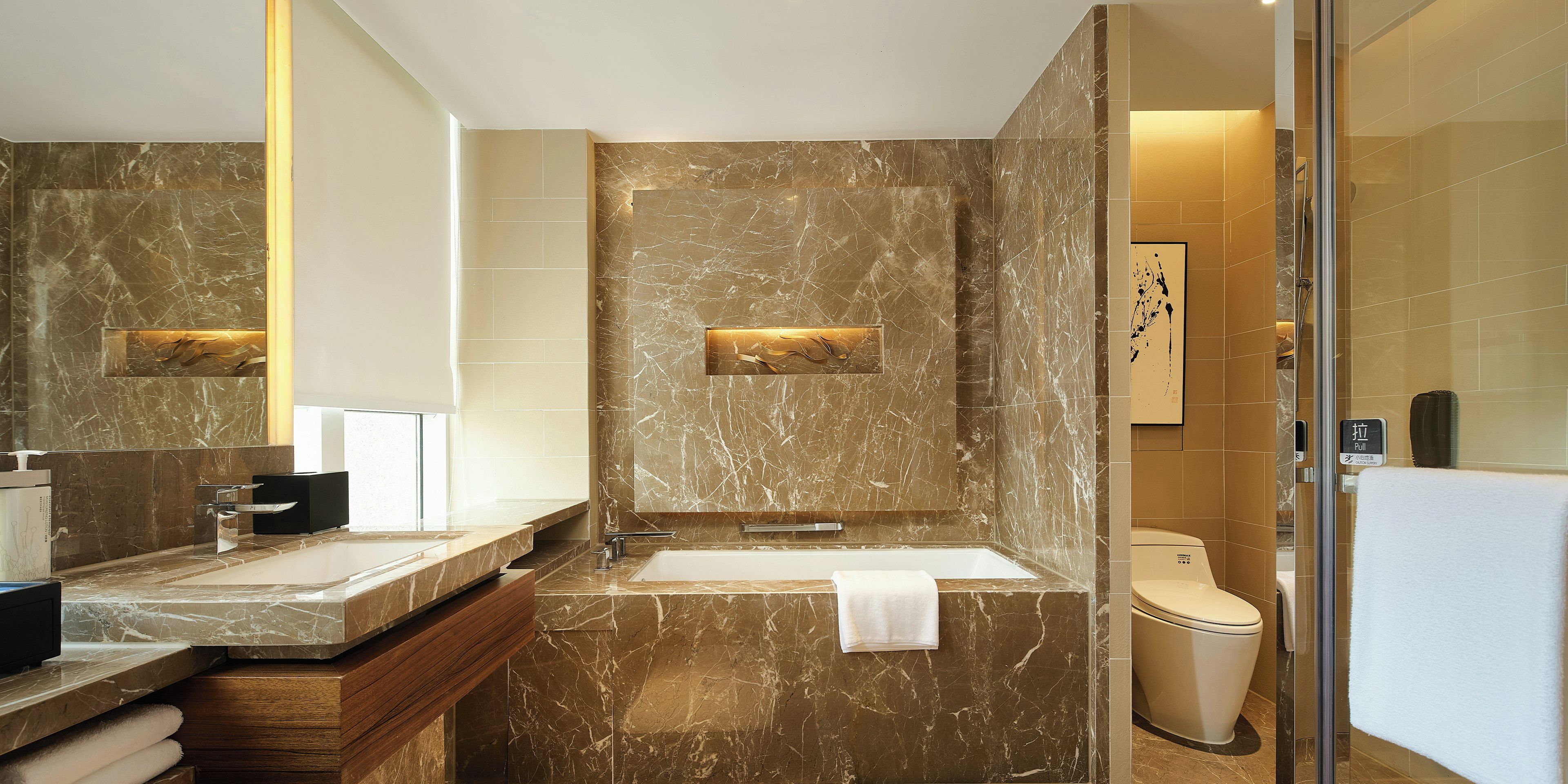 A modern bathroom with a marble vanity, a sink, and a toilet.