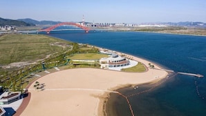 An aerial view of a coastal area with a beach, a bridge, and a waterfront property. - Hualuxe Ningbo Harbor City (Ningbo)