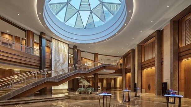 A spacious lobby with a central staircase, a large skylight, and multiple levels. - Hualuxe Ningbo Harbor City (Ningbo)