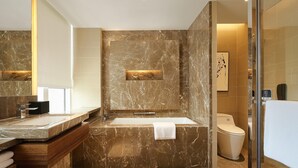 Een moderne badkamer met een marmeren wastafel, een grote spiegel en een douche met glazen wanden.