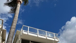 Un bâtiment à deux étages doté d’un balcon à l’étage supérieur, d’une porte de garage et d’un palmier au premier plan.