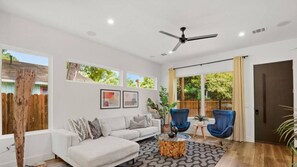 Relax in this stylish living room with a sofa, coffee table, and armchairs, offering a view of the outdoors.