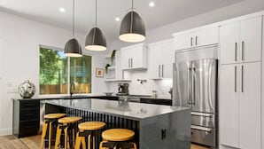 A modern kitchen with a central island, stainless steel appliances, and pendant lighting.
