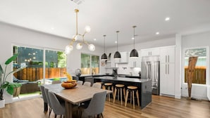 A modern kitchen with a central island, bar stools, and pendant lighting.