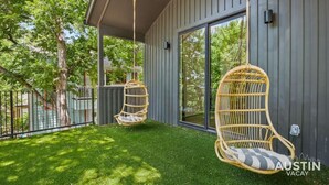 A covered patio with two wicker chairs and a glass door leading to a grassy area. - Holly #B xxxxxxxxxxx (Austin)