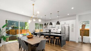 Una cocina moderna con una isla central, taburetes de bar e iluminación colgante.