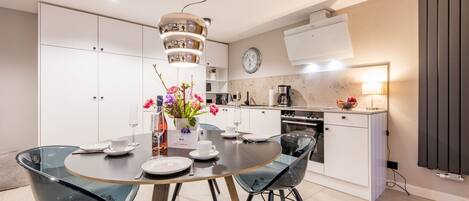 A modern kitchen with white cabinets, a built-in oven, and a coffee machine.