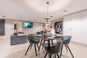 Una sala de estar moderna con comedor, que incluye una mesa redonda, sillas y un televisor montado en la pared.