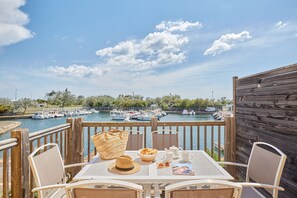 Eine Holzterrasse mit einem Tisch für zwei Personen mit Blick auf einen Yachthafen und Boote.