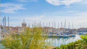 A marina with multiple boats docked, a clear sky, and buildings in the background. - Appartement Abordable avec Wi-Fi + Kitchenette (Agde)