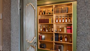 Una estantería de madera repleta de botellas y libros, presumiblemente una colección de vinos o licores.