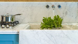 Una cocina con encimera de mármol, estufa, fregadero y una olla sobre la hornilla.