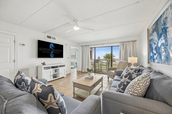 Ein modernes Wohnzimmer mit Fernseher, Sofa und Blick ins Freie.