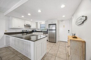 A modern kitchen with white cabinetry, a central island, stainless steel appliances, and a wooden sideboard.