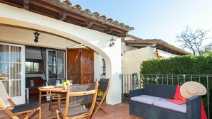 An outdoor patio with a table and chairs, a wicker sofa, and a covered area with a wooden door. - Stunning  villa for 4 people with pool and terrace (Torroella De Montgrí)