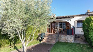 A house with a stone facade, a wooden deck, and a tree in the front yard. - Stunning  villa for 4 people with pool and terrace (Torroella De Montgrí)