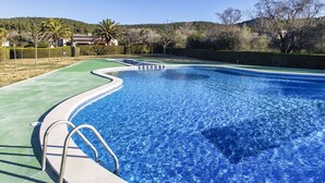 A swimming pool with a curved edge, a metal ladder, and a green deck area. - Stunning  villa for 4 people with pool and terrace (Torroella De Montgrí)