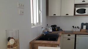 Ett kompakt kök med en bänkskiva i trä, en inbyggd spis, en mikrovågsugn och ett litet handfat.