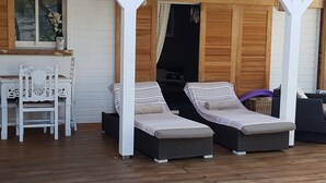Ett avskärmat utomhusområde med sittplatser, bestående av två solstolar och ett bord.