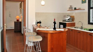 A kitchen with a wooden island, bar stools, a wine bottle, and a sink. - Cosy apartment for 6 people with WIFI, pool, TV, patio and pets allowed (Sperlonga)