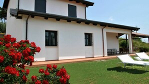 A two-story house with a white exterior, black window frames, and a covered porch area. - Cosy apartment for 6 people with WIFI, pool, TV, patio and pets allowed (Sperlonga)
