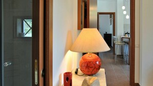 A hallway with a table featuring a lamp, a red mug, and a straw hat. - Cosy apartment for 6 people with WIFI, pool, TV, patio and pets allowed (Sperlonga)