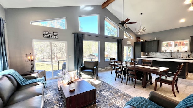 A modern living room with a fireplace, leather sofas, a coffee table, and a dining area with a kitchen in the background.