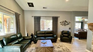 A spacious living room with a leather sofa, a coffee table, and a dining area in the background.