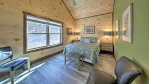 Ein Schlafzimmer einer Holzhütte mit einem Bett, zwei Nachttischen, einer Bank und einem Fenster.