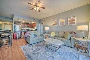 A spacious living room with a sofa, coffee table, and a dining area with chairs and a small kitchen in the background. - Lagoon-View Balcony! Family Resort Escape in PCB (Panama City Beach)