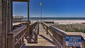 A wooden boardwalk leading to a beach with a lifeguard sign stating "NO LIFEGUARD ON DUTY SWIM AT OWN RISK". - Lagoon-View Balcony! Family Resort Escape in PCB (Panama City Beach)
