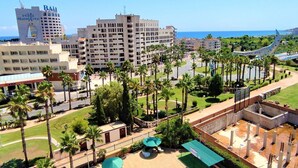 Ein Hotelkomplex mit mehreren Gebäuden, Palmen und freiem Blick auf das Meer.