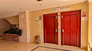 Eine Lobby mit zwei roten Türen, einer Treppe und einem Blumentopf.