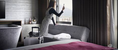 Et hotelværelse med seng, kuffert, en champagneflaske og udsigt til byen gennem vinduet.