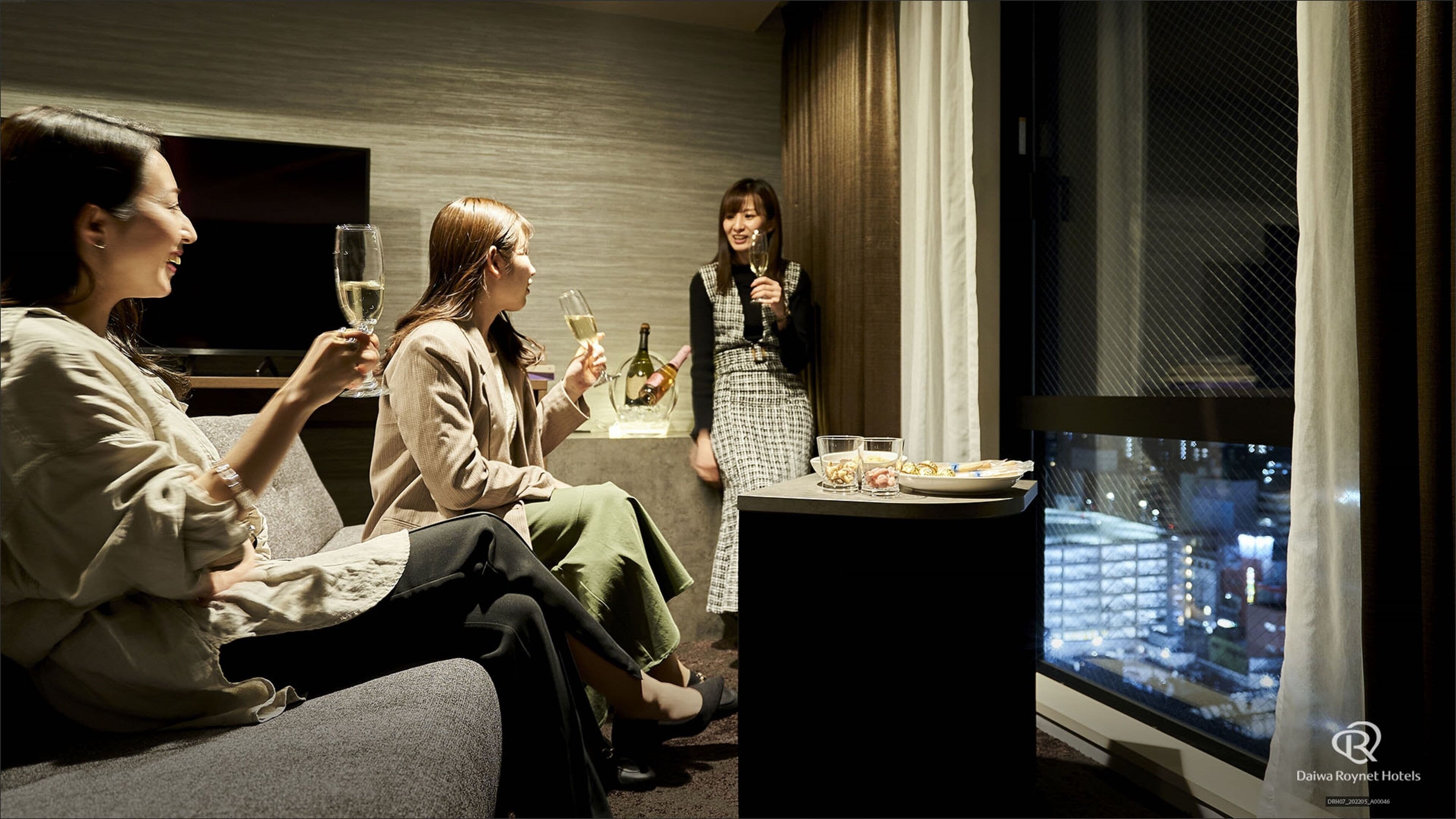 Habitación de hotel con vista a la ciudad, un televisor y una mesa con comida y bebidas.