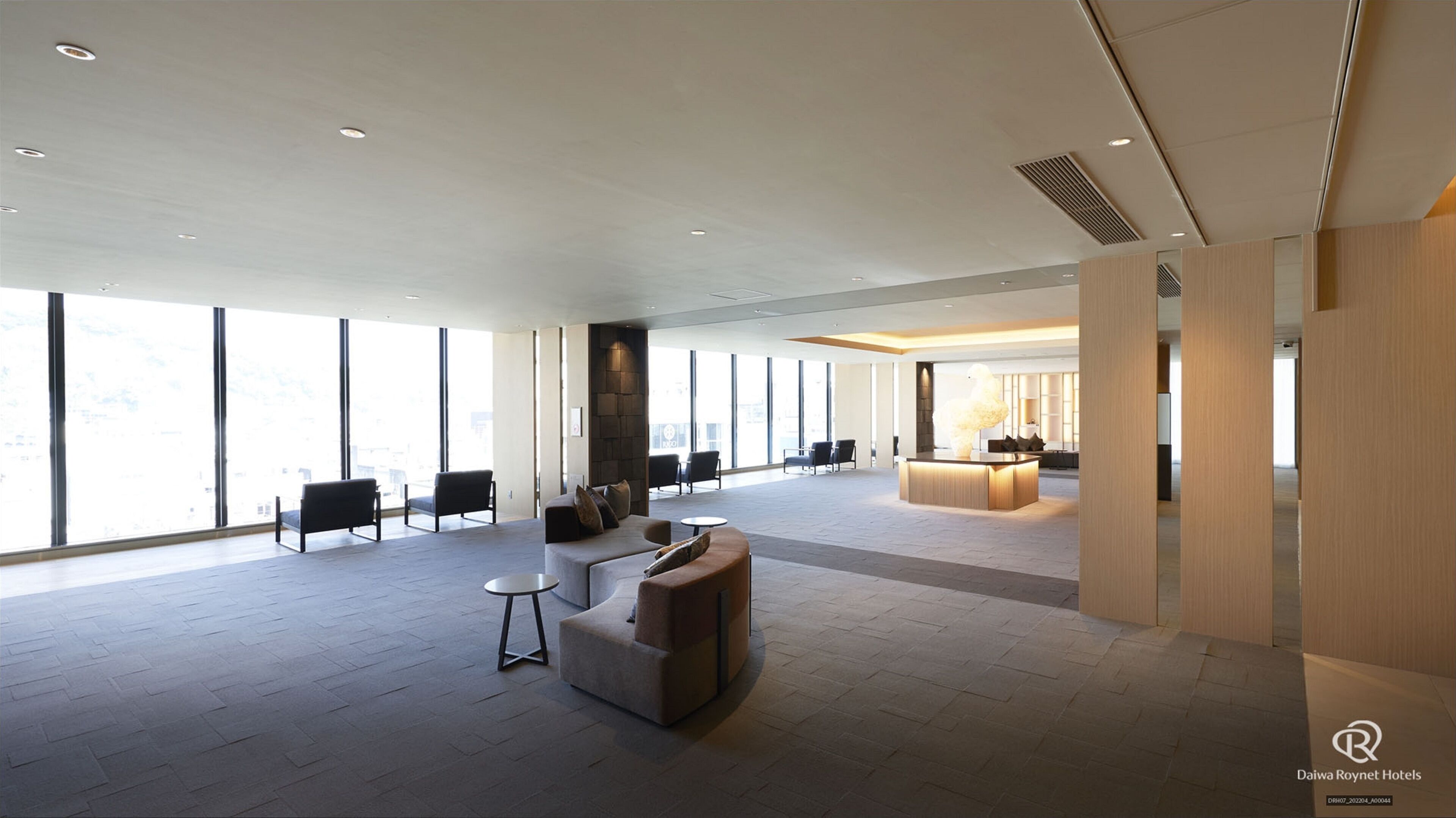 A spacious lobby with a reception desk, seating area, and large windows offering views.