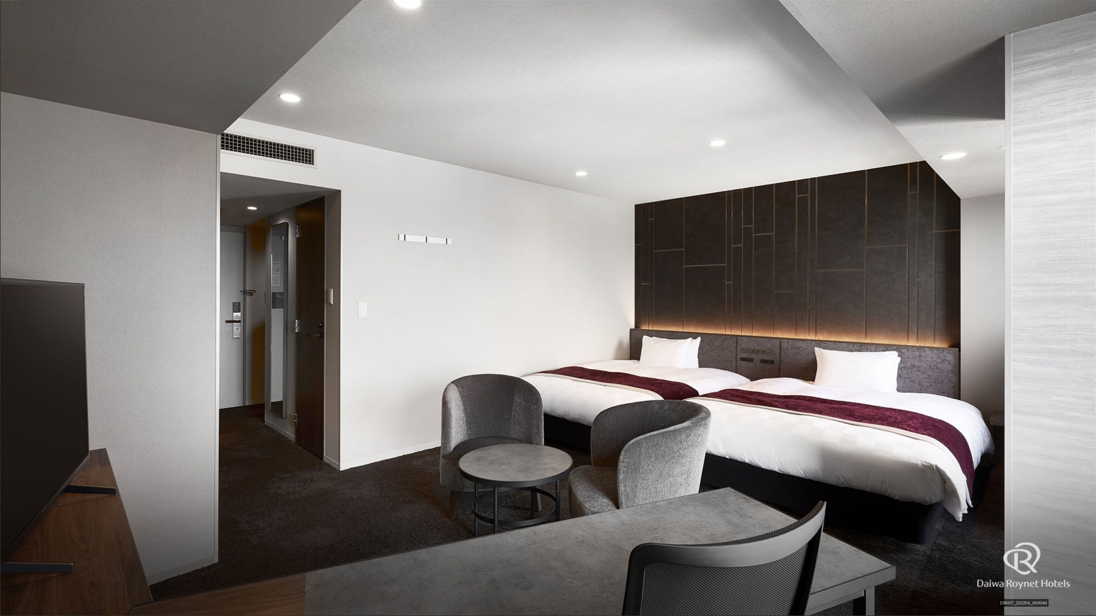 Habitación de hotel moderna con una cama grande, un escritorio y una silla. Hay un televisor y una mesita.