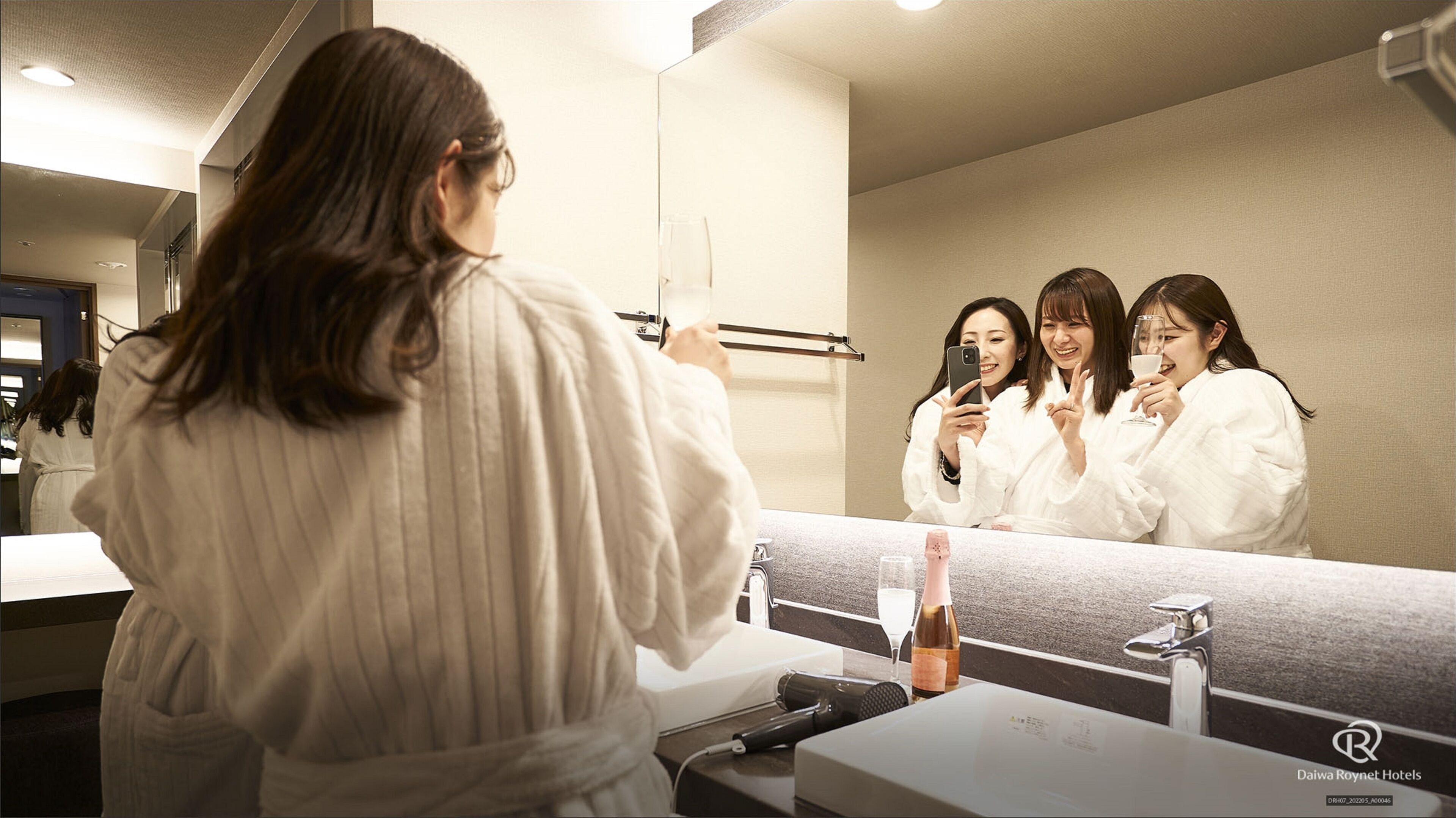 Ein Badezimmer in einem Hotel mit einem großen Spiegel, einem Föhn und einer Shampooflasche.
