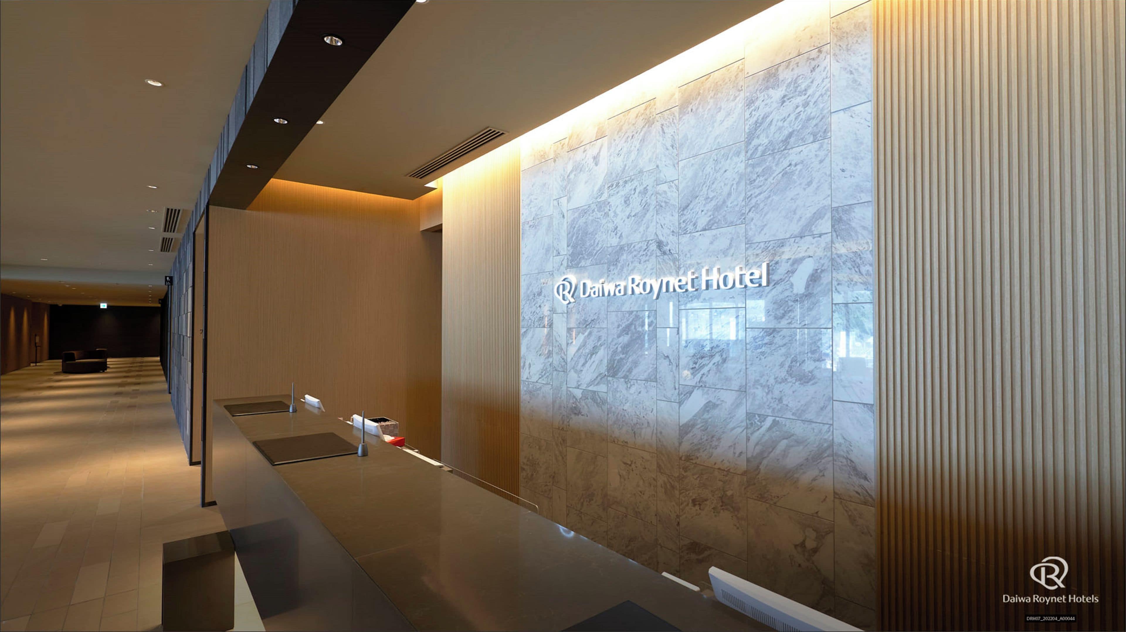 Een moderne hotel lobby met een marmeren muur en een receptiebalie.