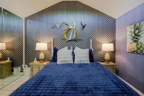 Quarto com cama grande, duas mesas de cabeceira e um mural na parede.