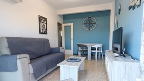 A living room with a sofa, a coffee table, a TV stand, and a wall clock. - 060 - Gran Playa 004 - comfortHOLIDAYS (Santa Pola)