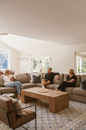 A modern living room with a sectional sofa, a coffee table, and a patterned rug. - Private 1+ acre, Bocce, Waterfall, Free Pool Heat (Santa Rosa)
