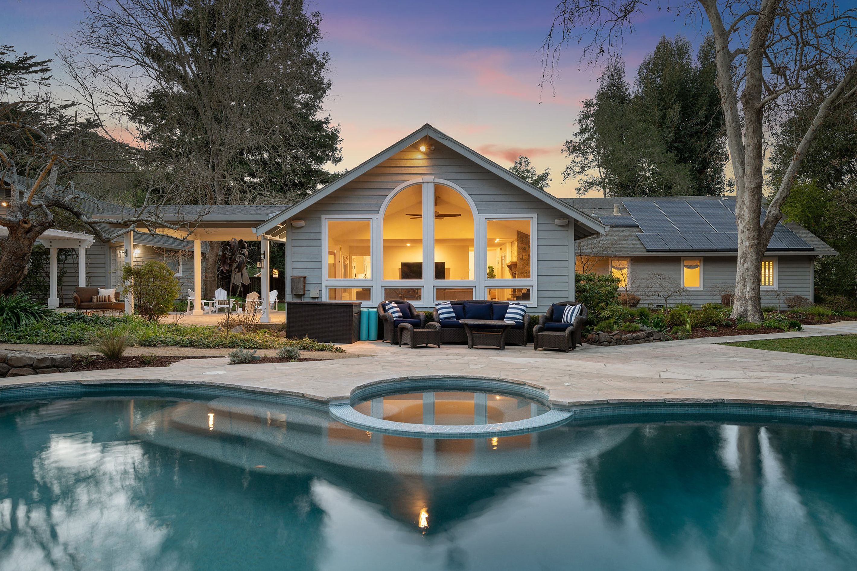 Ein Haus mit Pool, Sitzgelegenheiten im Freien und einer überdachten Terrasse.