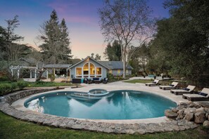 A residential property with a swimming pool, outdoor seating, and a house with a gabled roof. - Private 1+ acre, Bocce, Waterfall, Free Pool Heat (Santa Rosa)