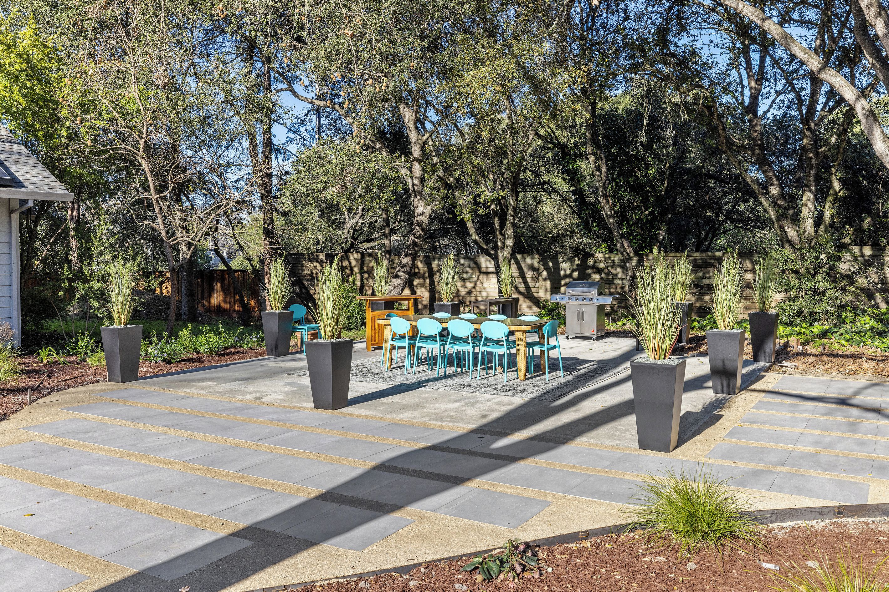 Un área de estar al aire libre con una mesa y sillas, rodeada de árboles y una valla de madera.