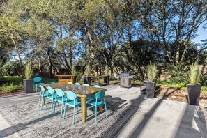An outdoor patio with a table and chairs, a barbecue grill, and a garden area. - Private 1+ acre, Bocce, Waterfall, Free Pool Heat (Santa Rosa)