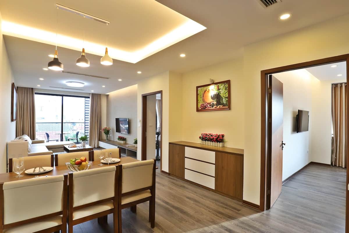 A modern hotel room with a dining area, a living space, and a bedroom.